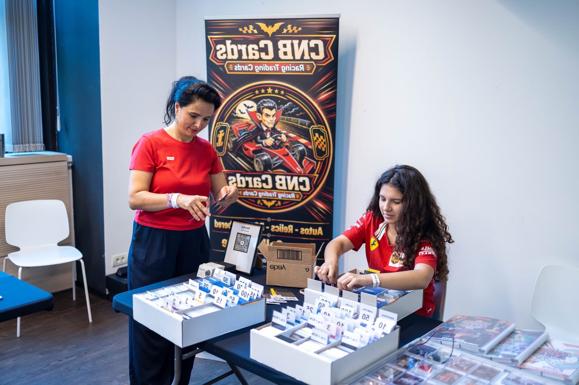 Două persoane răsfoiesc cutii cu cartonașe la un stand, la o ediție anterioară Card Show